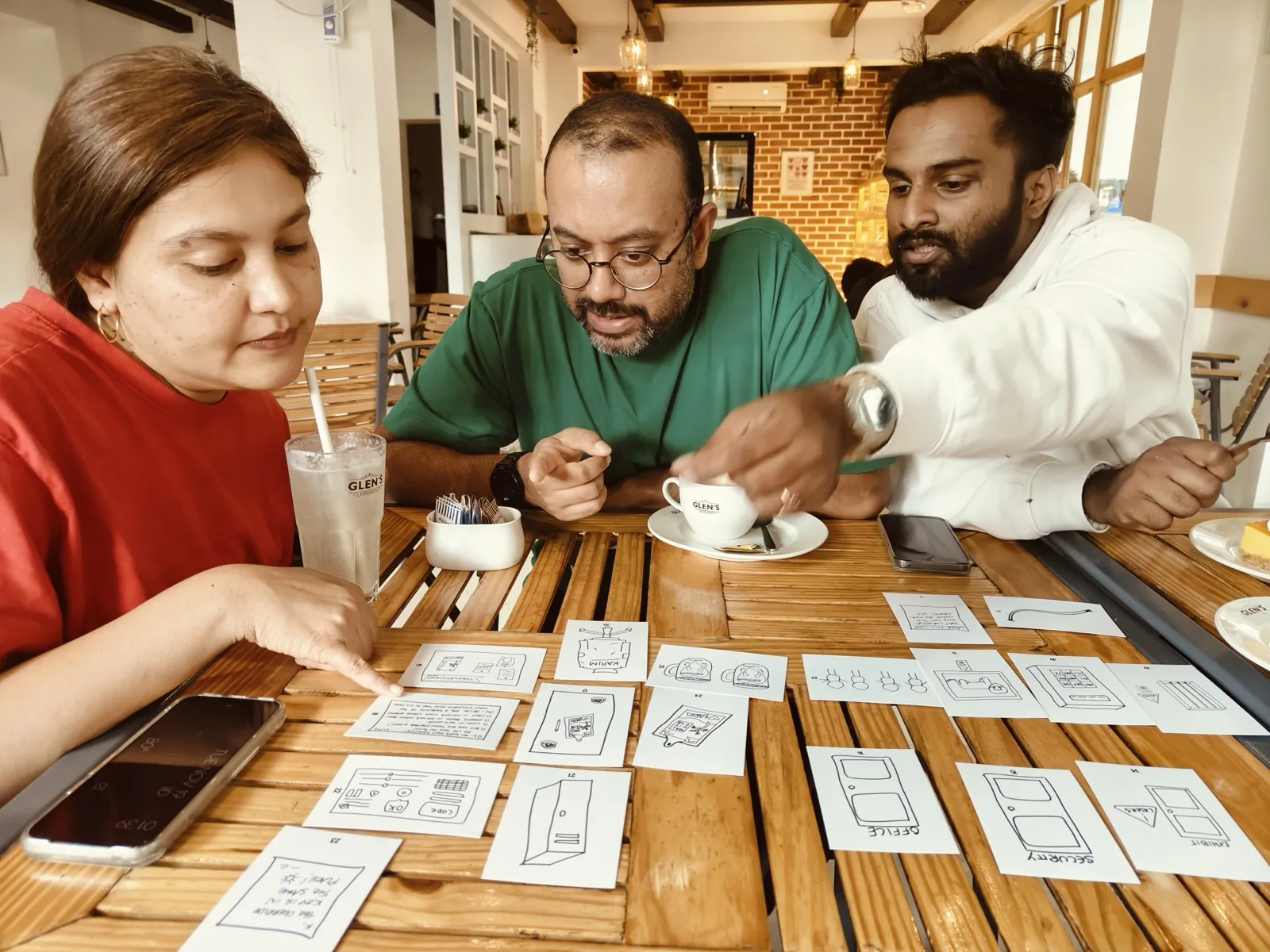 Small team collaborating over illustrated game cards at a table