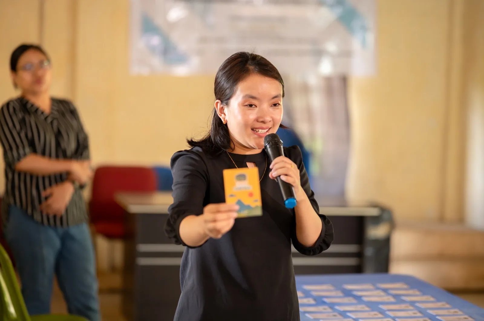 Facilitator presenting with a microphone while holding a game card